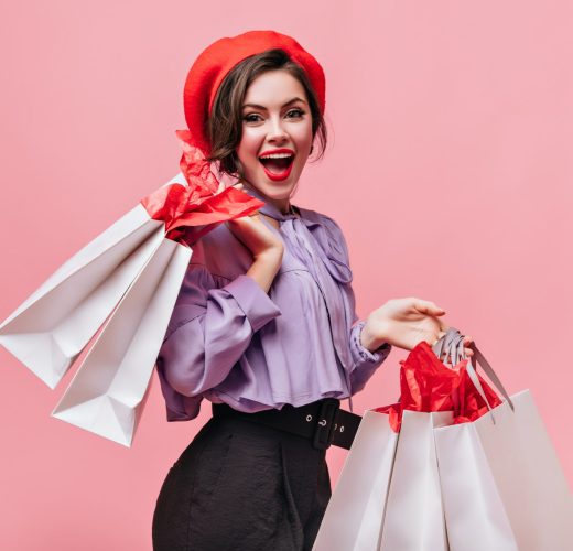 woman-in-red-hat-black-trousers-and-light-blouse-laughs-and-poses-with-packages-after-shopping-min